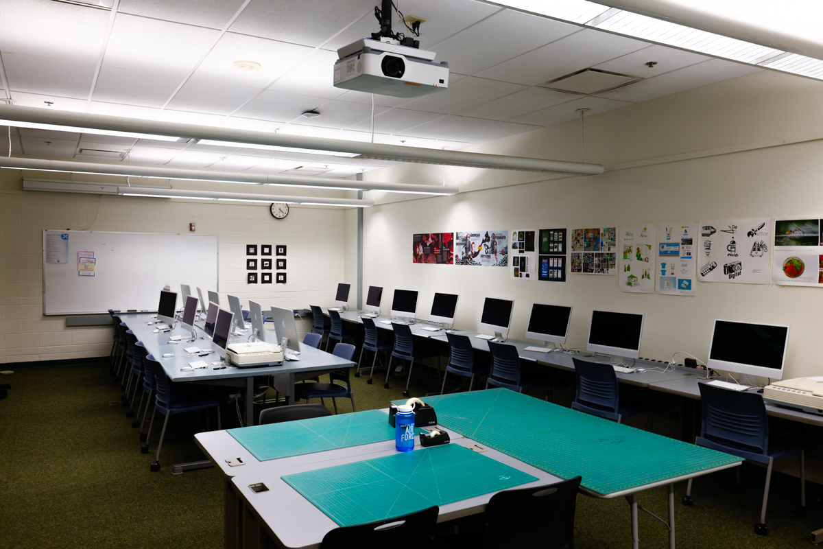 A classroom equipped with multiple computer workstations and a projector, suitable for digital design or technology classes.