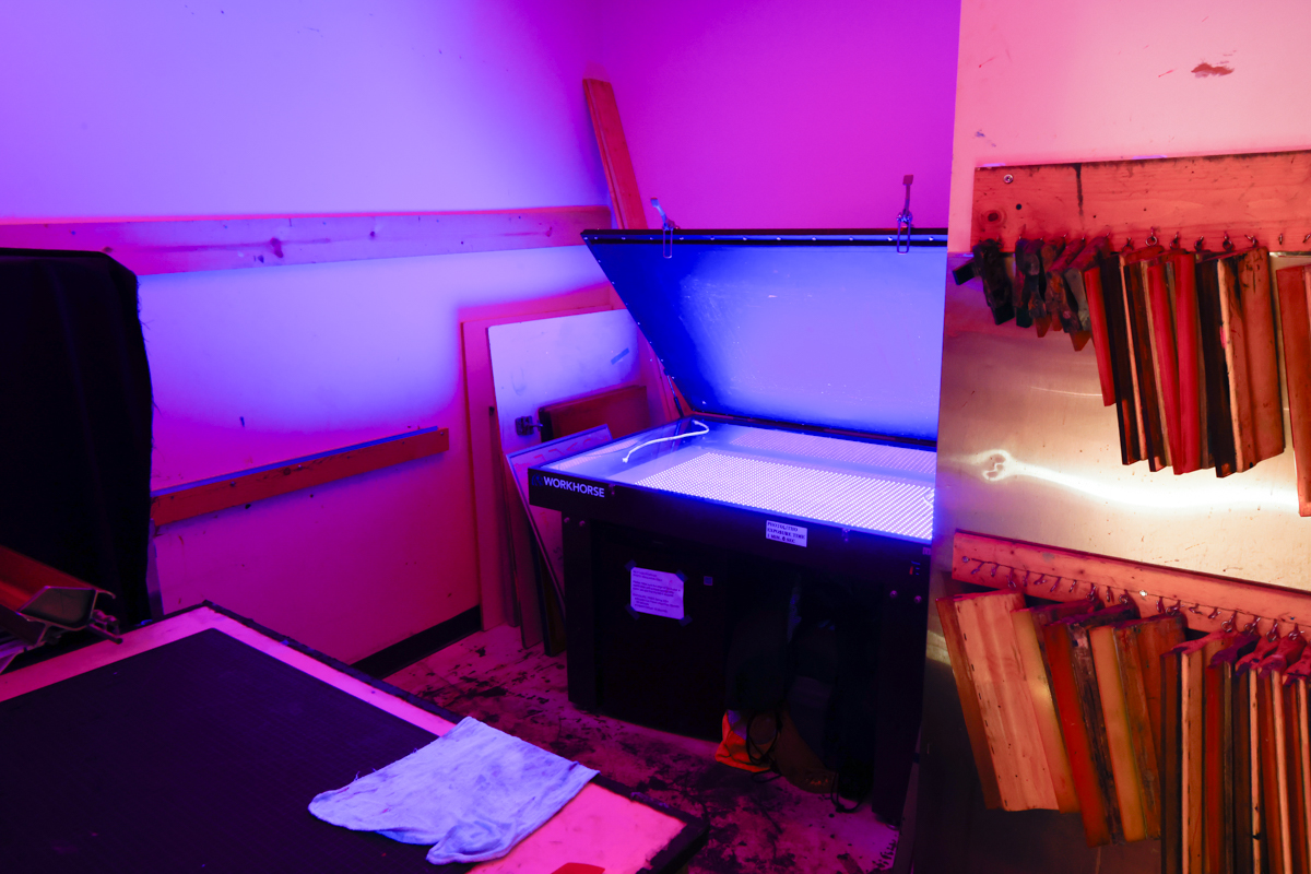 Interior of a workspace featuring a lightbox with a glowing blue top and wooden screens on the wall, illuminated by purple lighting.