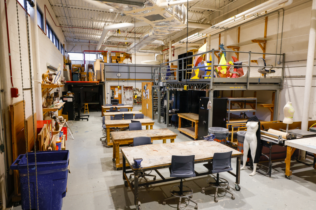 A spacious art studio featuring work tables, storage areas, and tools for creativity and crafting. The environment is organized with various materials and art supplies visible.