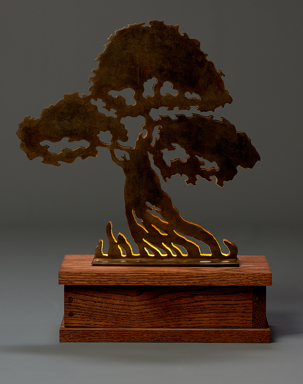 A decorative sculpture of a tree with intricate branches and roots, mounted on a wooden base.