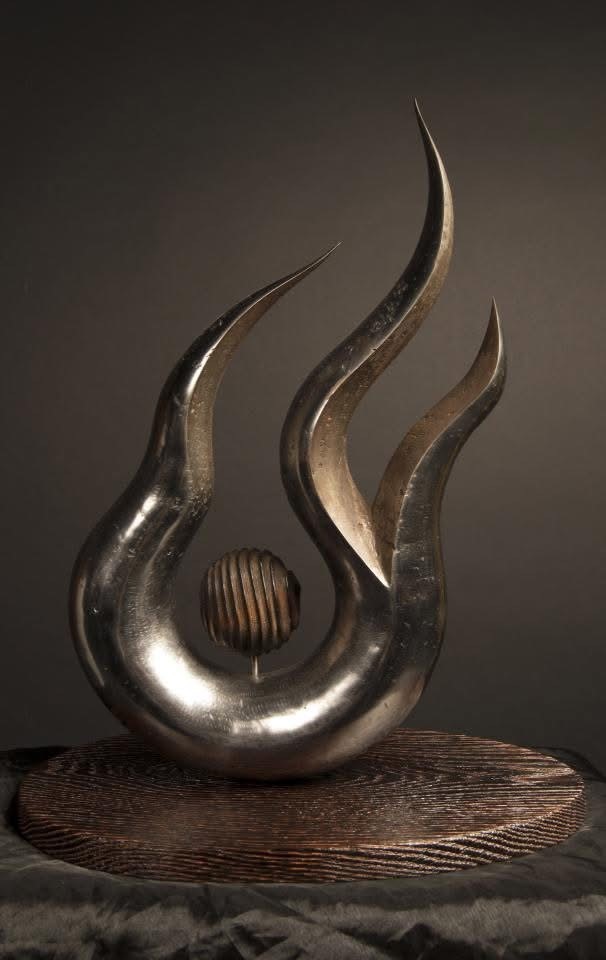 Modern metallic sculpture featuring flowing forms and a central spherical element.