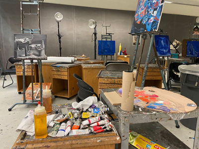 painting equipment on table with two paintings displayed on easels
