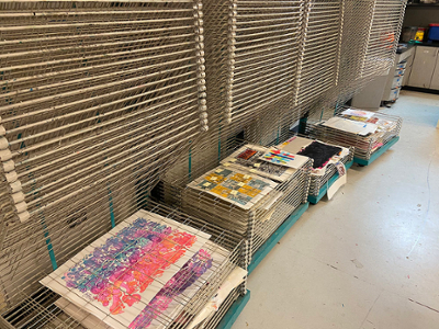 paintings and drawings laid out in piles for drying and storage