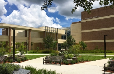 Outside view of the Biology building 59 with benches in front and clouds in the background