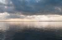 Sunset over the water covered by clouds