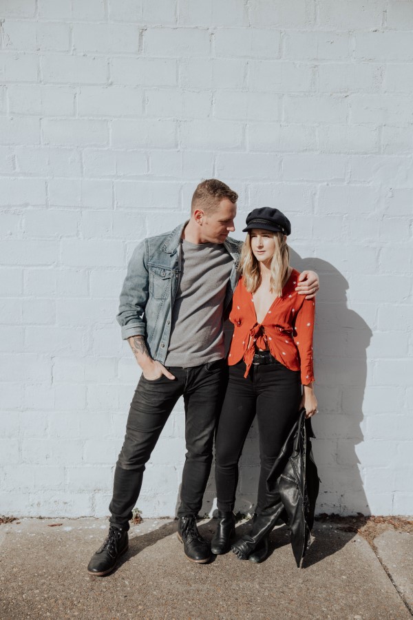 Kayla Barnhart and Guy standing in front of a grey brick wall.