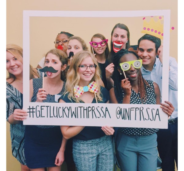 Students hold a frame and various facial features on sticks.