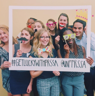 Students are having fun in a photo boot  with masks on sticks.