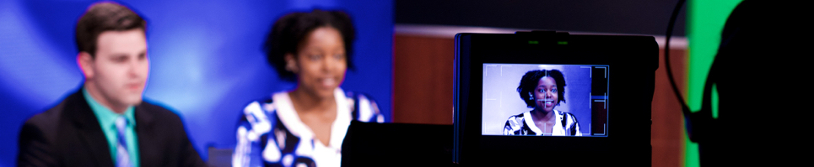 Anchors of a news station reporting from the news desk while a camera films them