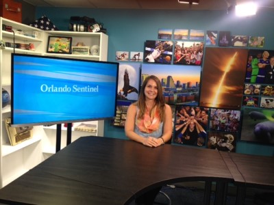 Emilee Speck sitting at a table on the set of the Orlando Sentinel desk.
