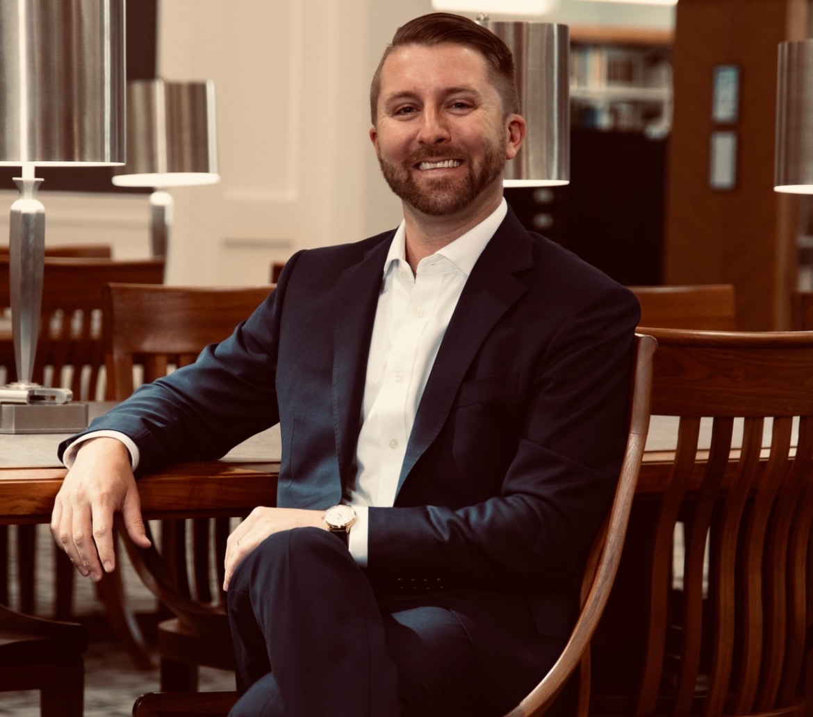Tyler Holder seated at a wood table in a suit