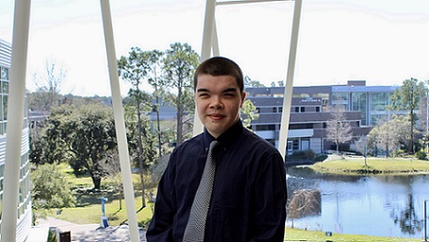 Alumni, Kai Edu, poses in front of UNF pond.