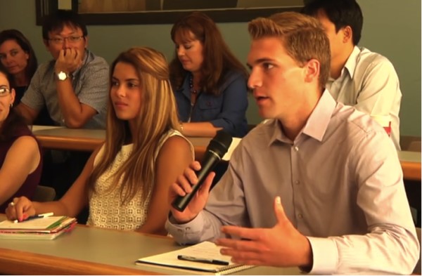 Using a microphone, a student addresses the panel during the industry discussion.