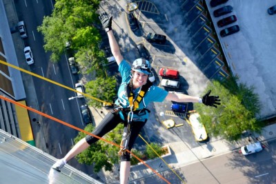 Tracey Collins hanging by ropes off building.