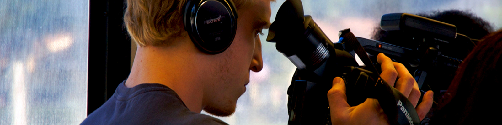 Student looking through lens of film camera while wearing headset