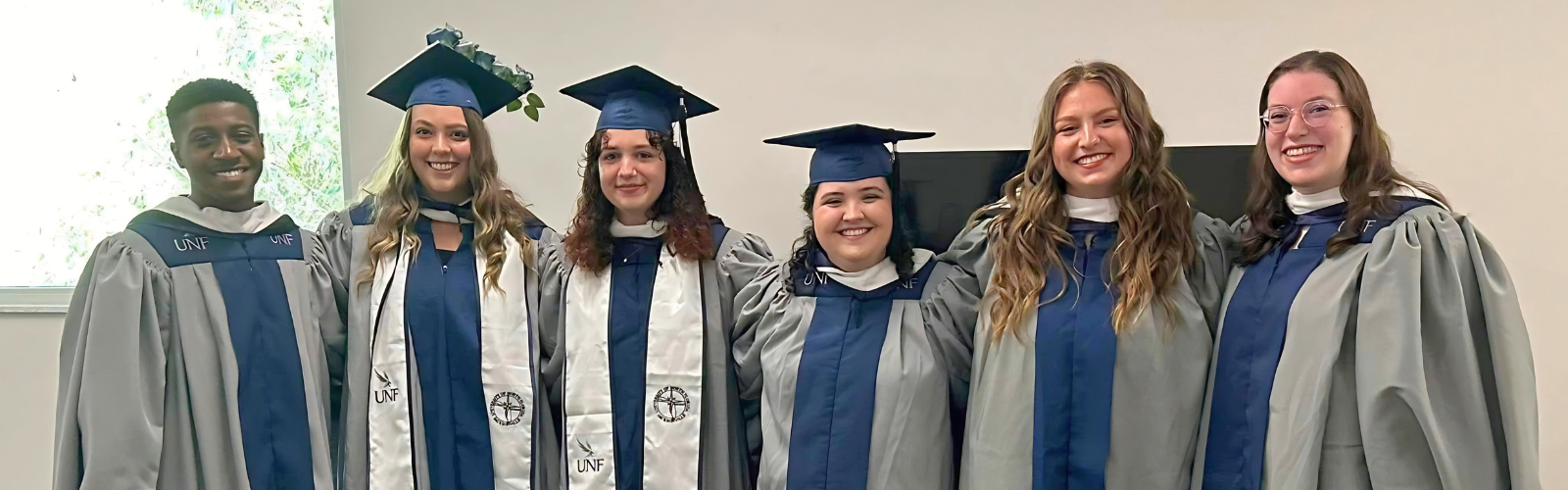 Graduates in UNF regalia smiling together