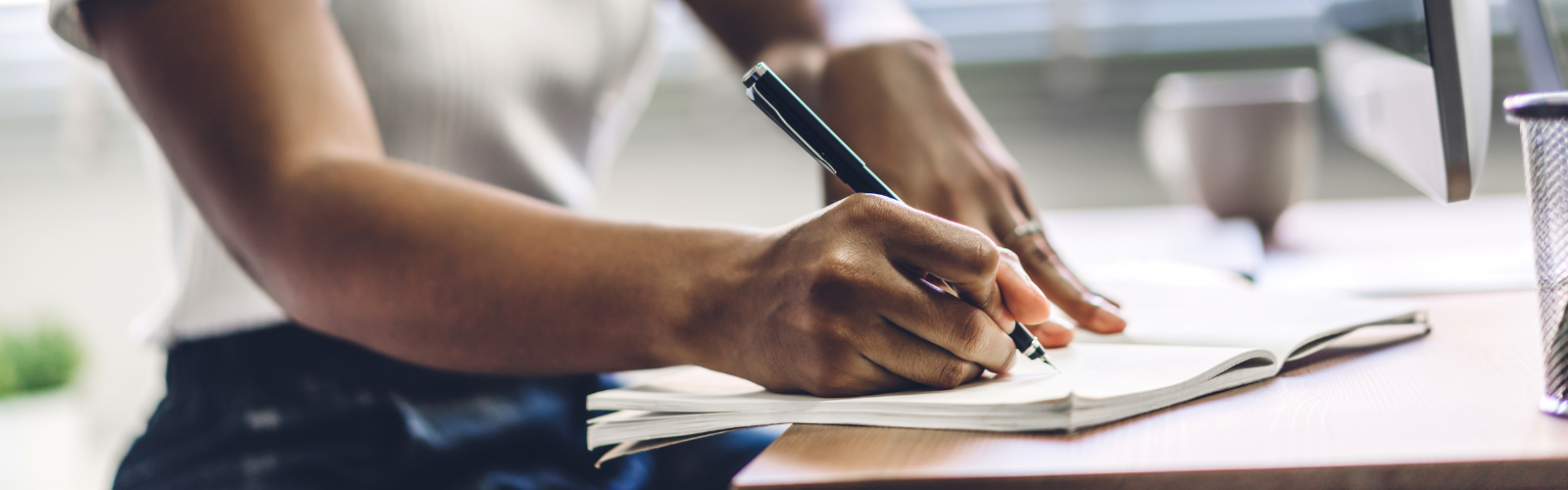 Person writing in a notebook with a pen