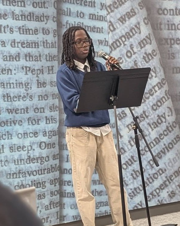 Student reading from a microphone during an event.
