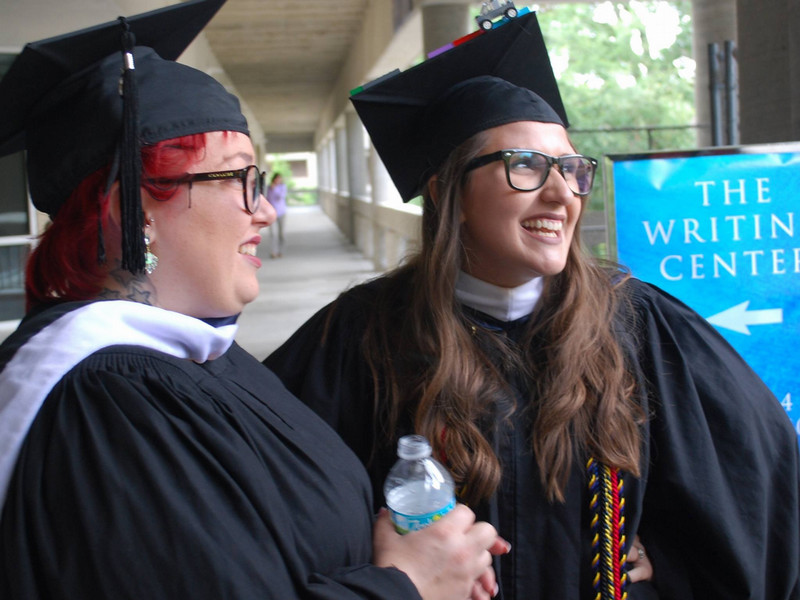 Two UNF English M.A. graduates celebrate outside the Writing Center on commencement day