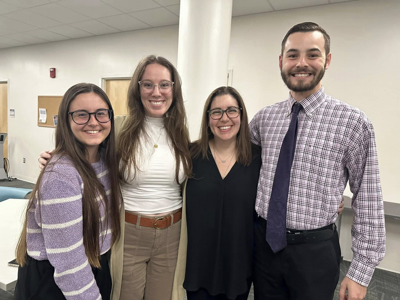 Four UNF English graduate students smile together at a department event.