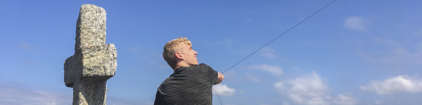 Student pulls measuring line near historic stone monument