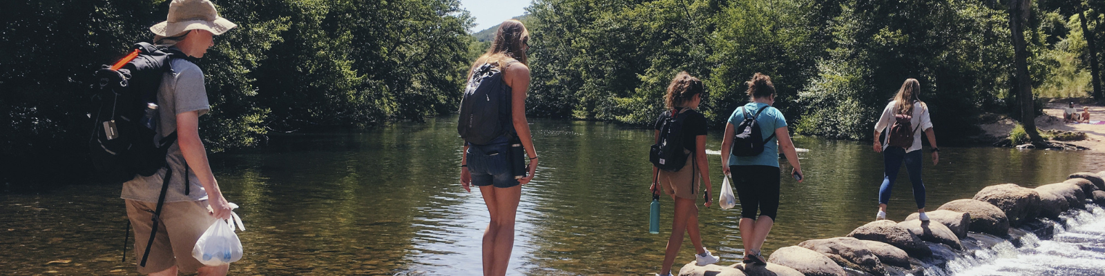 Students hike across a shallow river during field research