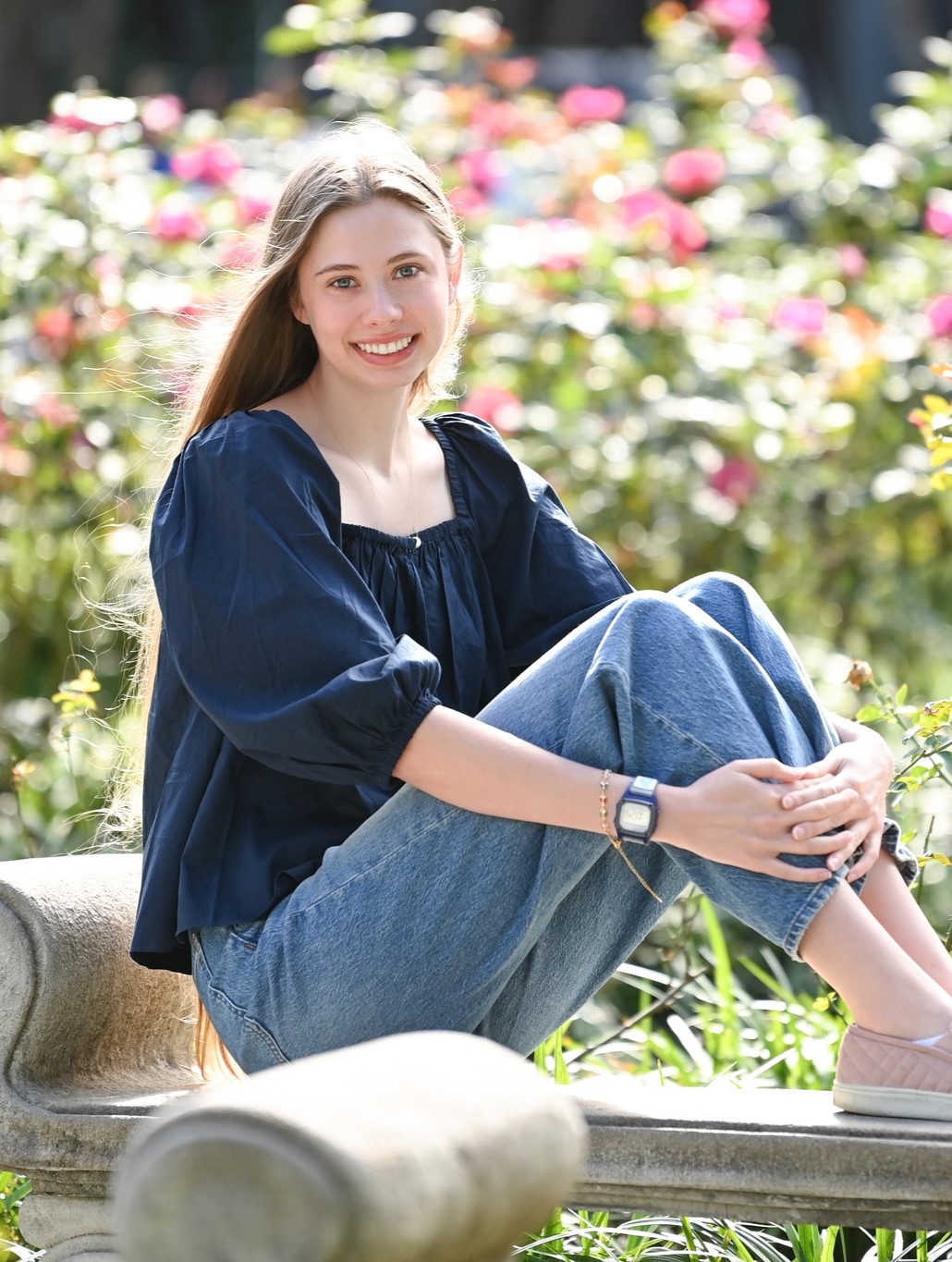 Peri Manwell smiling on a stone bench