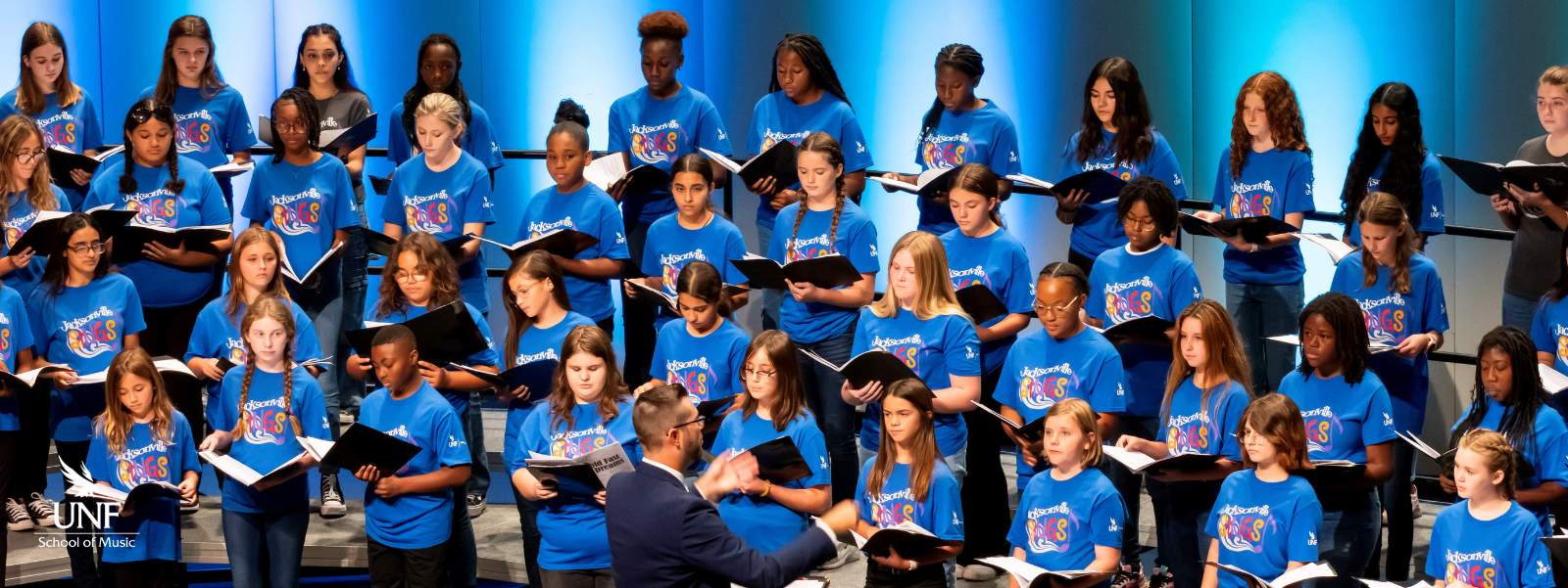Students in blue shirts singing in choir.