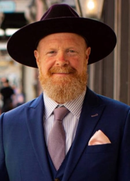 Man in blue suit wearing a hat.