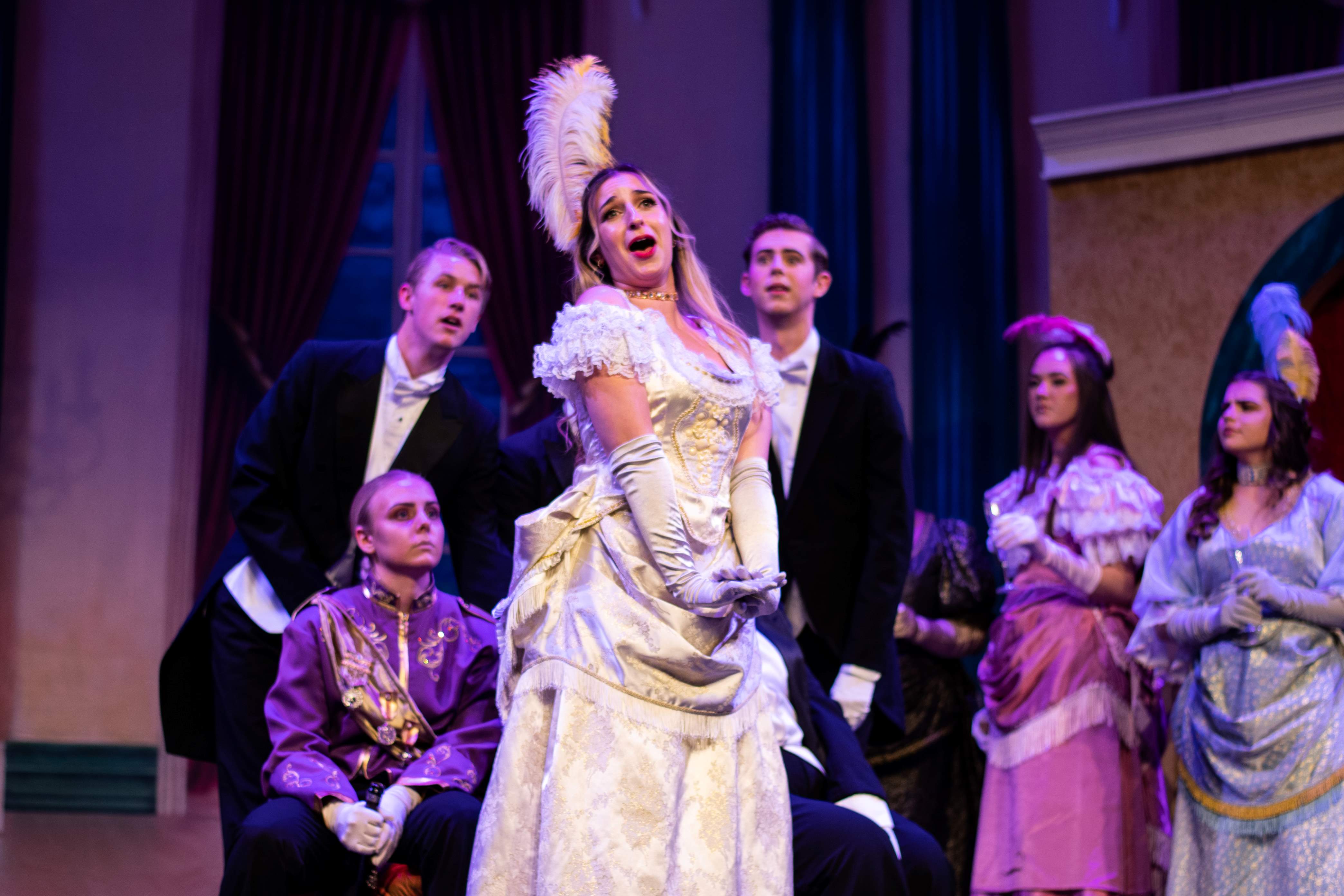 Woman in fancy white dress singing.