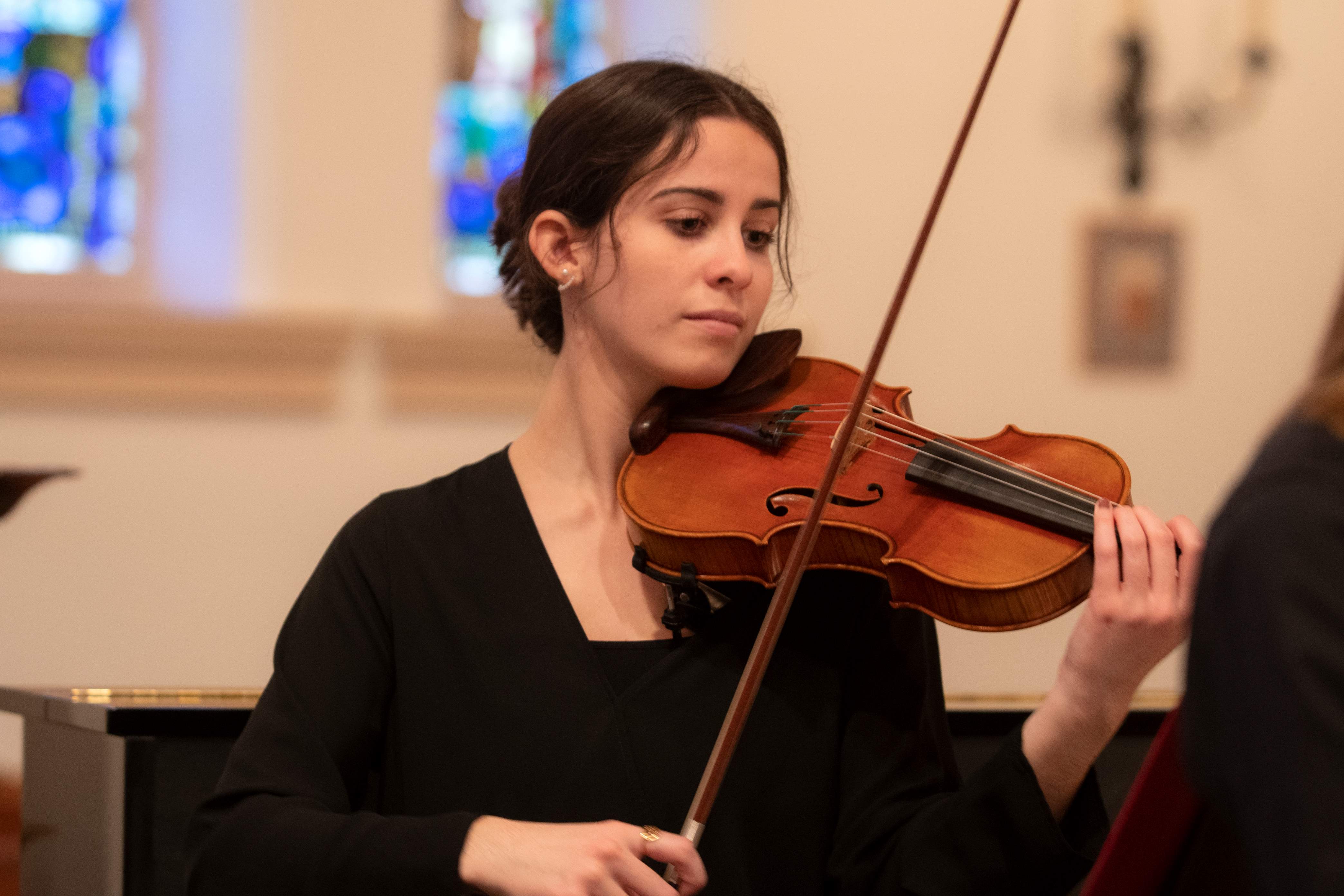 Woman with dark hair playing violin.