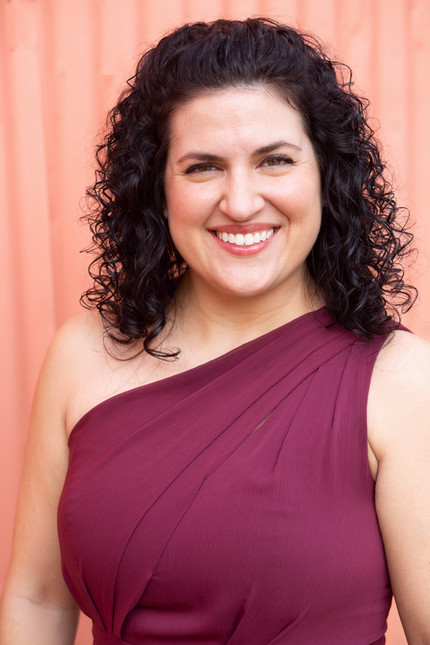 Woman with curly brown hair wearing fuchsia dress. 