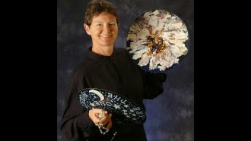 Woman with short hair holding cymbals in either hand.