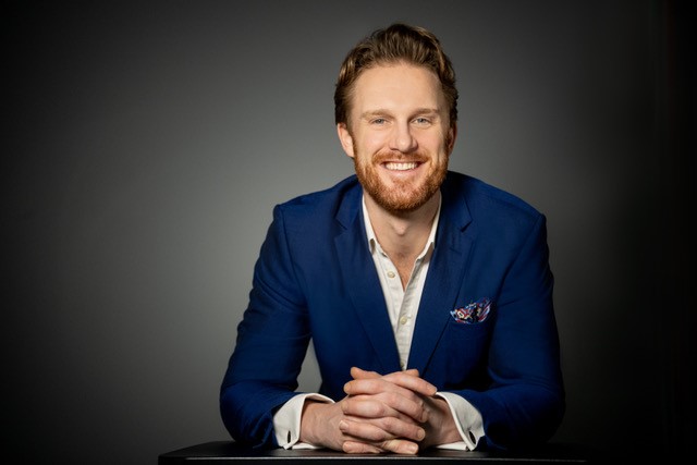 Man wearing navy suit and smiling.