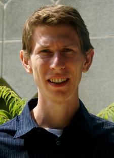 Caucasian male with sandy brown hair squinting slightly and looking at camera. 