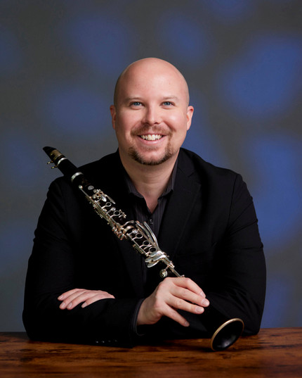 Man in black long-sleeved shirt holding clarinet. 