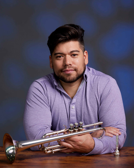 Man holding trumpet while leaning on desk.