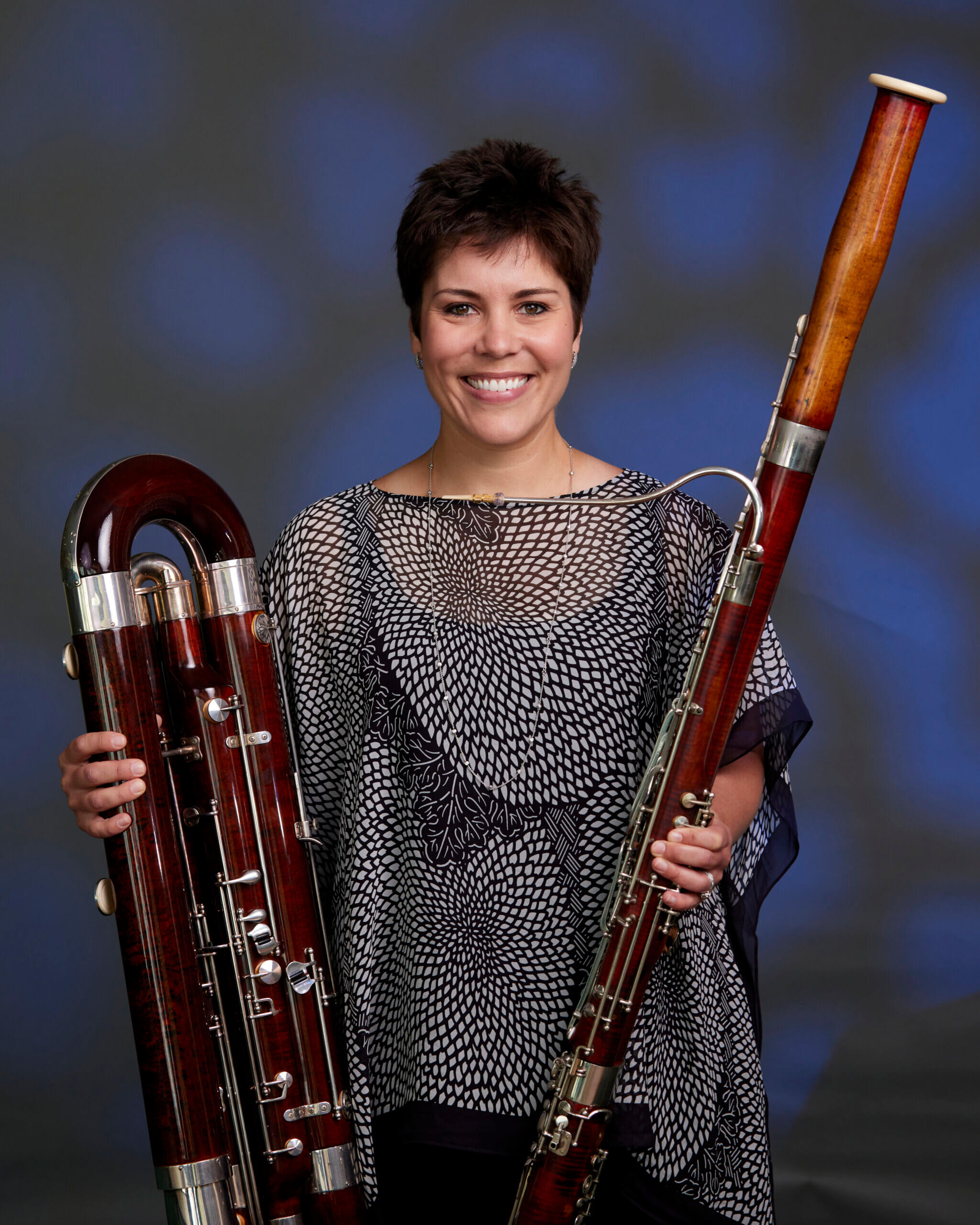 Woman with short black hair holding two parts of bassoon. 