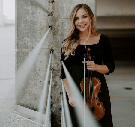 Woman in black dress holding a violin.