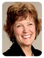 Woman with short, brunette hair wearing a black collard blazer and smiling for the camera. 