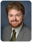 Man in gray suit and tie smiling at camera.