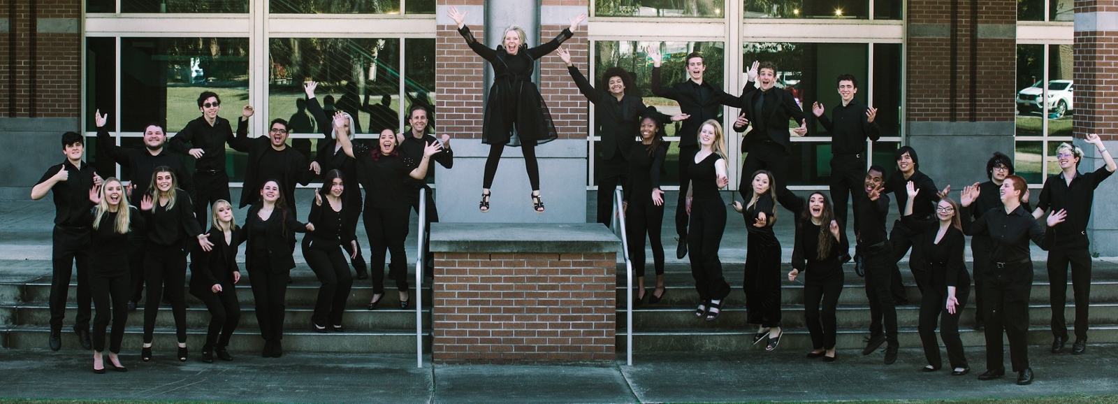 music students leaping into the air in front of building