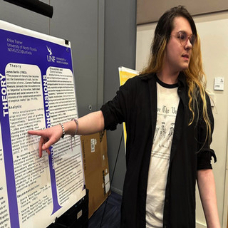 Student pointing to and discussing their poster