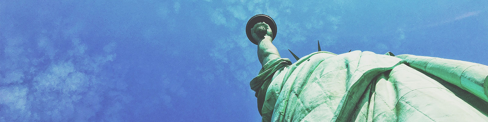 Looking up at the Statue of Liberty from its base with a blue sky background