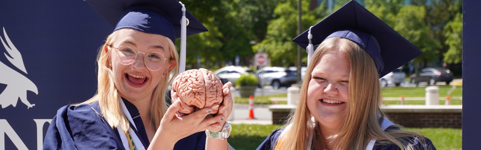 two graduates holding brain model