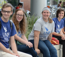A group of college students sitting down wearing shirts that say "UNF Hicks Honors College"