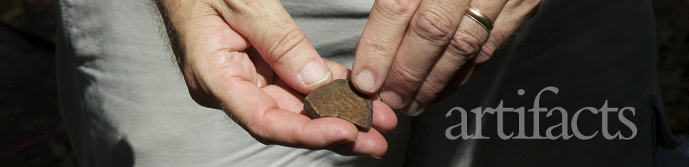 Man holding a piece of rock and text artifacts