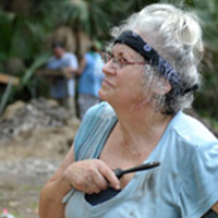 Vicki Rolland looking to the left while holding a walkie talkie at an Archaeological site