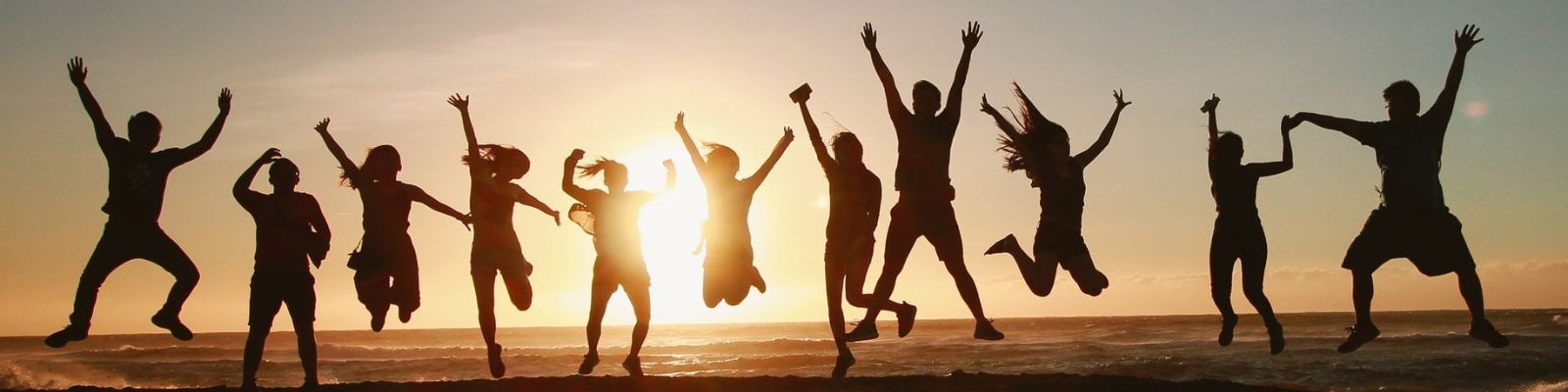 Group of students jumping at the beach