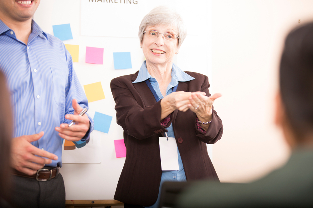 An elderly women using sign language in a business setting